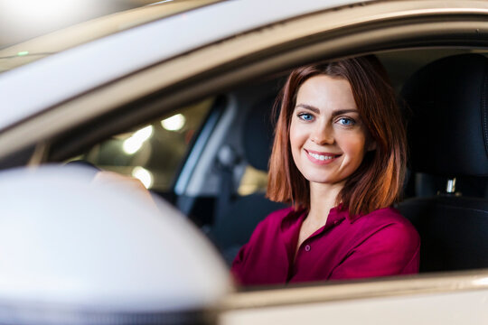 Happy redheaded businesswoman driving car