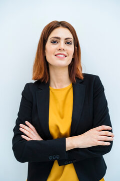 Smiling businesswoman standing with arms crossed against white background