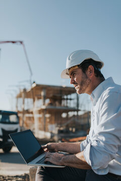 Thoughtful architect sitting with laptop at construction site