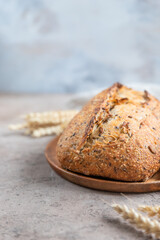 Loaf of artisan sourdough bread with wheat ears and linen napkin on concrete background. Tartine with multigrain seeds.