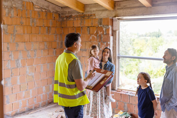 Architect having discussion with family at construction site