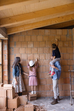 Mature man and woman with daughters drawing on brick wall