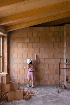 Girl With Chalk Drawing On Brick Wall At Construction Site