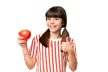 Little caucasian girl holding an apple over isolated background with thumbs up because something...