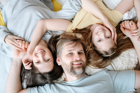 Smiling mother, father and daughter lying together at home