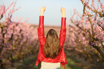 Back view of a woman in red celebrating in a flowered field