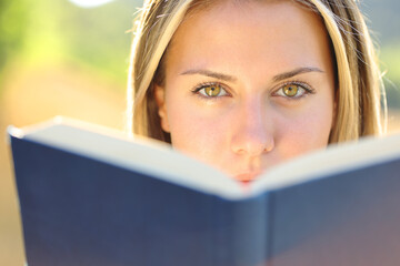 Beautiful woman reads a book looking at you
