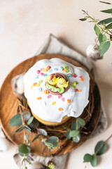 Easter composition with traditional Orthodox sweet bread. Kulich decorated with meringue icing, candy shaped eggs. Holiday concept.