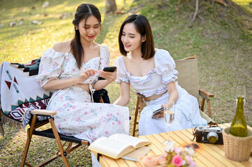 Relaxed Asian women in beautiful dresses are watching a video on a mobile phone together
