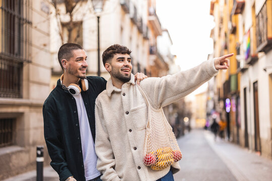 Smiling gay mn with boyfriend pointing amidst buildings