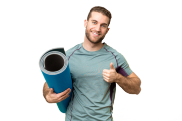Young sport man going to yoga classes while holding a mat over isolated chroma key background with thumbs up because something good has happened