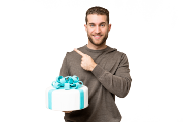 Young handsome blonde man holding birthday cake over isolated chroma key background pointing to the side to present a product