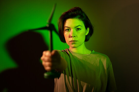 Businesswoman showing wind turbine against colored background