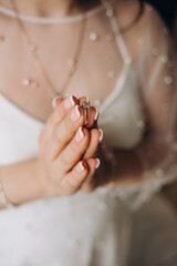 Hands of the bride in a white wedding dress with a gold engagement ring with a diamond close-up. Bride touches the ring with her fingers