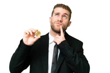 Young business blonde man holding a Bitcoin over isolated chroma key background having doubts while looking up