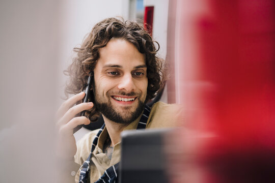 Happy businessman with tablet PC talking on smart phone 