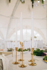 Wedding. Banquet. The chairs and round table for guests, served with cutlery, flowers and crockery and covered with a tablecloth