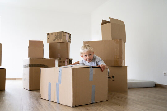 Little boy pushing cardboard box at home