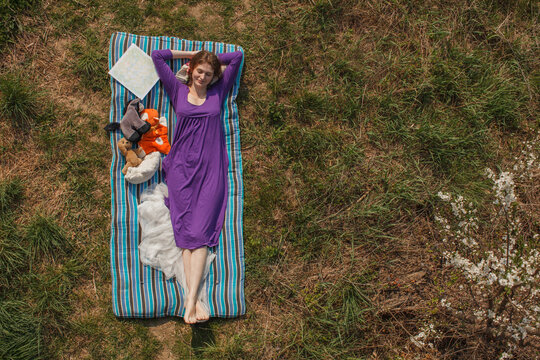 Smiling young woman relaxing on mattress at garden