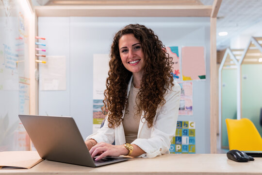 Portrait of smiling brunette businesswoman using laptop in office