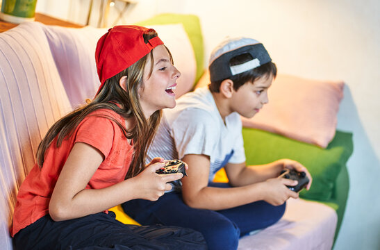 Children playing video games together in living room