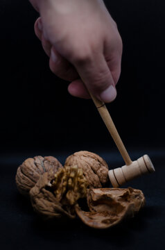 a man's hand breaks a nut shell with a hammer