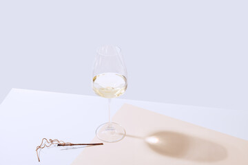 A glass of white wine is on the table. Light background.
