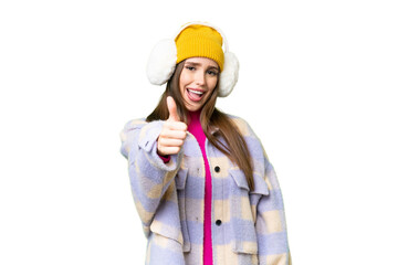 Young woman wearing winter muffs over isolated chroma key background with thumbs up because something good has happened