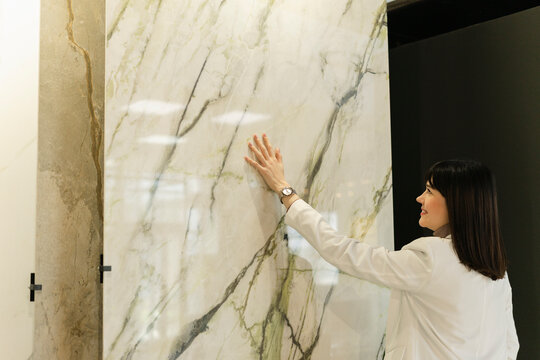 Woman touching marble plate in showroom