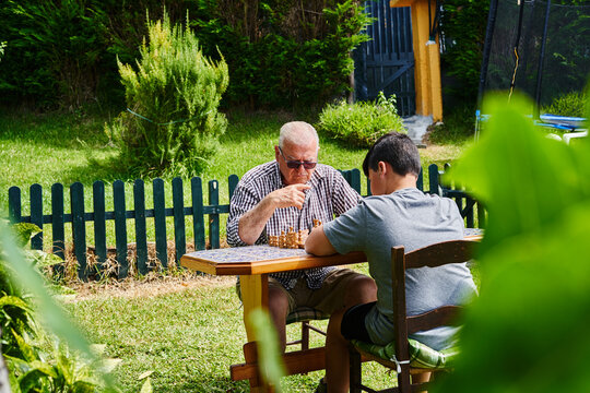 Grandfather and grandson playing chess in the garden