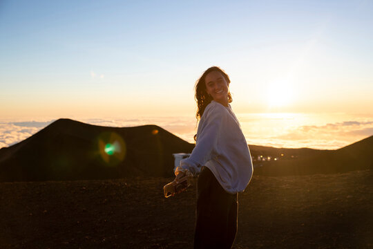 female poses for photo at sunset on top of Mauna Kea