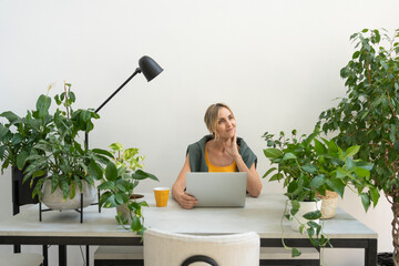 Thoughtful freelancer sitting with laptop at desk