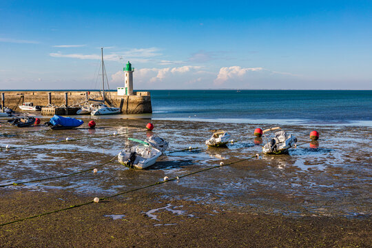 France, Nouvelle-Aquitaine, La Flotte, Boats left on beach with lighthouse in background