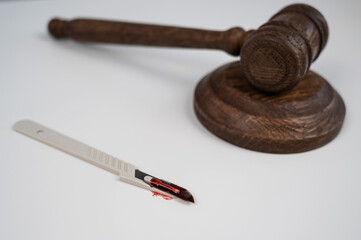 A scalpel covered in blood and a judge's wooden gavel.