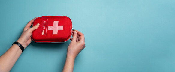 A woman opens a first aid kit. Home first aid kit on a blue background.