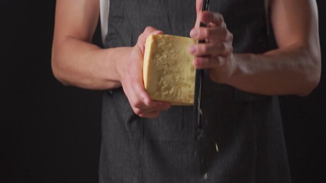 manos rallando queso parmesano con un rallador en camara lenta