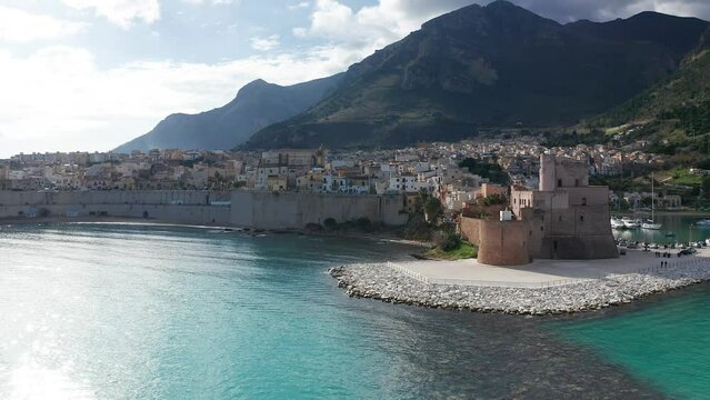 Aerial Flying Over Turquoise Waters In The Gulf Of Castellammare Towards Castello Arabo Normanno On Sunny Day
