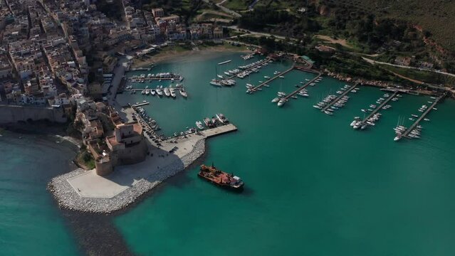 Aerial View Of Castellammare Del Golfo Port In Sicily With Castello Arabo Normanno On Sunny Day.  Ascending Shot, Dolly Back