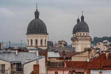 Obraz premium Landscape of ancient church domes in the centre of Lviv (Lwow, Lvov), Ukraine, on overcast rainy day, scenic view of roofs in old town, historical buildings from observation deck, touriust landmark