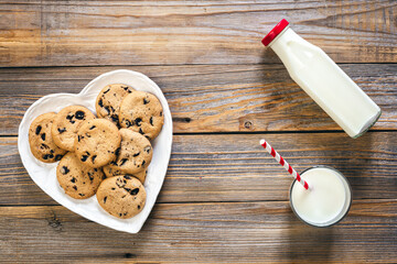 Plate with cookies, and a glass of milk on a wooden background, flat lay.