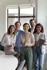 Diverse team of cheerful happy business employees meeting in office, looking at camera, smiling,...