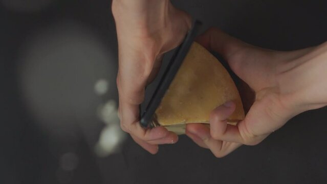 manos rallando queso parmesano con un rallador en camara lenta