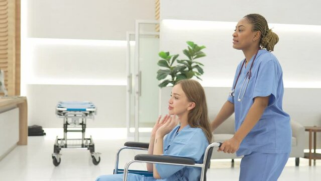 Nurse wheeling patient in wheelchair through lobby of Hospital.
