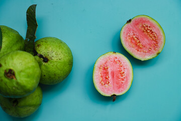 Flat lay of fresh guava fruit and guava juice served on blue table background