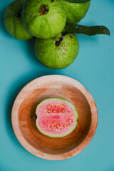 Flat lay of fresh guava fruit and guava juice served on blue table background