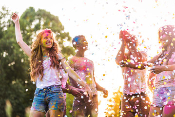 Multiethnic group of happy playful friends playing and having fun with holi colorful powder at the...