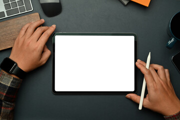 Creative man holding stylus pen and using digital tablet over black leather. Empty screen for text...