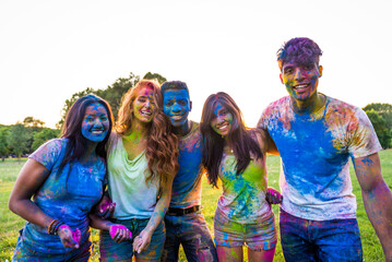 Multiethnic group of happy playful friends playing and having fun with holi colorful powder at the...
