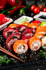 Sushi rolls with tuna, salmon, cream cheese, flying fish caviar, greens, soy sauce, wasabi, ginger and chopsticks.