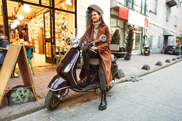 Portrait of attractive young cheerful woman riding moped scooter © fotofabrika